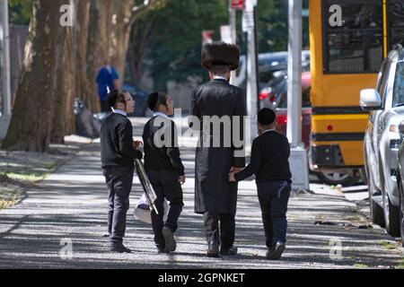 Eine chassidisch-jüdische, ähnlich gekleidete Familie kehrt von den Sukkos-Diensten der Synagoge zurück. In Williamsburg, Brooklyn, New York City. Stockfoto