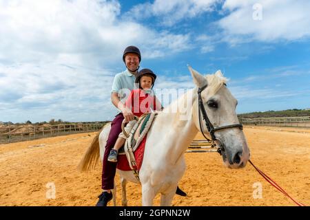 Vater und Sohn genießen Reiten im Paddock Stockfoto