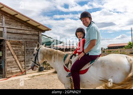 Vater und Sohn genießen Reiten im Paddock Stockfoto