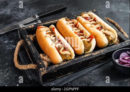 Veganer Hot-Dog mit verschiedenen Belägen und fleischloser vegetarischer Wurst. Schwarzer Hintergrund. Draufsicht Stockfoto