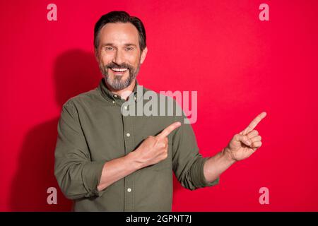 Foto Porträt Geschäftsmann trägt grünes Hemd zeigt leeren Raum isoliert hellen roten Hintergrund Stockfoto