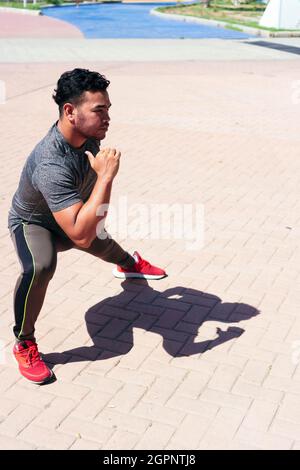 Schöner Mann, der sein Bein streckt und sich zum Training aufwärmt. Stockfoto
