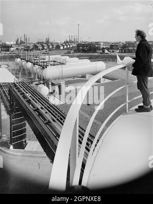 Ein Mann, der von einem hohen Standpunkt aus über die Coryton Calor Gas-Tankstelle auf die Batterie der Lagertanks am Standort blickt. Laing Civil Engineering führte die Tiefbaufundamente für die Calor-Tankstelle in Coryton, nordöstlich der Coryton-Ölraffinerie, durch. H. J. Cash war der Hauptauftragnehmer für die elektrischen und mechanischen Arbeiten. Der Standort sollte die neue Zentrale der Eastern Region für die Betriebs- und Vertriebsabteilung der Calor Gas (Holding) Company bilden. Stockfoto