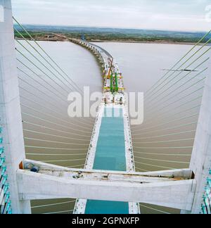 Ein Blick nach Osten von der Spitze des zweiten Severn Crossings während der Bauarbeiten, der die Arbeiten zeigt, die zur Verbindung der Einheiten auf dem darunter liegenden Brückendeck durchgeführt wurden. Die zweite Severn Crossing dauerte vier Jahre und war ein gemeinsames Tiefbauprojekt zwischen Laing Civil Engineering und dem französischen Unternehmen GTM. Die Arbeiten begannen im April 1992 und die Eröffnungszeremonie fand später am 5. Juni 1996 statt. Die Überfahrt ist eine Kabelbrücke, die sich über 5000 Meter über den Fluss Severn erstreckt, der England und Wales verbindet, 3 Meilen stromabwärts von der Severn Bridge, die 1966 eröffnet wurde. Stockfoto