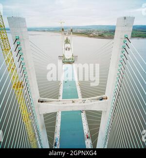 Ein Blick nach Westen von der Spitze des zweiten Severn Crossings während der Bauarbeiten, der die Arbeiten zeigt, die zur Verbindung der Einheiten auf dem darunter liegenden Brückendeck durchgeführt wurden. Die zweite Severn Crossing dauerte vier Jahre und war ein gemeinsames Tiefbauprojekt zwischen Laing Civil Engineering und dem französischen Unternehmen GTM. Die Arbeiten begannen im April 1992 und die Eröffnungszeremonie fand später am 5. Juni 1996 statt. Die Überfahrt ist eine Kabelbrücke, die sich über 5000 Meter über den Fluss Severn erstreckt, der England und Wales verbindet, 3 Meilen stromabwärts von der Severn Bridge, die 1966 eröffnet wurde. Stockfoto