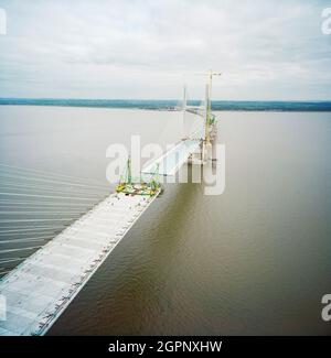 Ein Blick nach Osten von der Spitze des zweiten Severn Crossings während der Bauarbeiten, der die Arbeiten zeigt, die ausgeführt wurden, um die Deckeinheiten der Brücke unten zu verbinden. Die zweite Severn Crossing dauerte vier Jahre und war ein gemeinsames Tiefbauprojekt zwischen Laing Civil Engineering und dem französischen Unternehmen GTM. Die Arbeiten begannen im April 1992 und die Eröffnungszeremonie fand später am 5. Juni 1996 statt. Die Überfahrt ist eine Kabelbrücke, die sich über 5000 Meter über den Fluss Severn erstreckt, der England und Wales verbindet, 3 Meilen stromabwärts von der Severn Bridge, die 1966 eröffnet wurde. Stockfoto