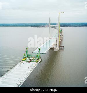 Ein Blick nach Osten von der Spitze des zweiten Severn Crossings während der Bauarbeiten, der Kabel zeigt, die das Deck der Brücke stützen, und die Arbeiten, die ausgeführt werden, um die Deckseinheiten zu verbinden. Die zweite Severn Crossing dauerte vier Jahre und war ein gemeinsames Tiefbauprojekt zwischen Laing Civil Engineering und dem französischen Unternehmen GTM. Die Arbeiten begannen im April 1992 und die Eröffnungszeremonie fand später am 5. Juni 1996 statt. Bei der Überfahrt handelt es sich um eine Kabelbrücke, die sich über 5000 Meter über den Fluss Severn erstreckt, der England und Wales verbindet, 3 Meilen stromabwärts vom Severn Br Stockfoto