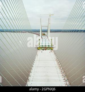 Ein Blick nach Osten entlang des Decks der Brücke während des Baus des zweiten Severn Crossings, der Kabel zeigt, die das Deck der Brücke stützen, und die Arbeiten, die ausgeführt werden, um die Deckseinheiten zu verbinden. Die zweite Severn Crossing dauerte vier Jahre und war ein gemeinsames Tiefbauprojekt zwischen Laing Civil Engineering und dem französischen Unternehmen GTM. Die Arbeiten begannen im April 1992 und die Eröffnungszeremonie fand später am 5. Juni 1996 statt. Die Überfahrt ist eine Kabelbrücke, die sich über 5000 Meter über den Fluss Severn erstreckt, der England und Wales verbindet, 3 Meilen stromabwärts von Th Stockfoto