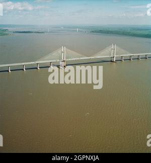 Eine Luftaufnahme nach Nordosten entlang des Flusses Severn, die den zweiten Severn Crossing im Vordergrund mit der Severn Bridge dahinter zeigt. Die zweite Severn Crossing dauerte vier Jahre und war ein gemeinsames Tiefbauprojekt zwischen Laing Civil Engineering und dem französischen Unternehmen GTM. Die Arbeiten begannen im April 1992 und die Eröffnungszeremonie fand später am 5. Juni 1996 statt. Die Überfahrt ist eine Kabelbrücke, die sich über 5000 Meter über den Fluss Severn erstreckt, der England und Wales verbindet, 3 Meilen stromabwärts von der Severn Bridge, die 1966 eröffnet wurde. Stockfoto