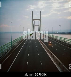 Ein Blick auf den zweiten Severn Crossing, der in der Dämmerung entlang des Decks der Brücke blickt. Die zweite Severn Crossing dauerte vier Jahre und war ein gemeinsames Tiefbauprojekt zwischen Laing Civil Engineering und dem französischen Unternehmen GTM. Die Arbeiten begannen im April 1992 und die Eröffnungszeremonie fand später am 5. Juni 1996 statt. Die Überfahrt ist eine Kabelbrücke, die sich über 5000 Meter über den Fluss Severn erstreckt, der England und Wales verbindet, 3 Meilen stromabwärts von der Severn Bridge, die 1966 eröffnet wurde. Stockfoto