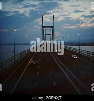 Ein Blick auf den zweiten Severn Crossing, der nachts auf das Deck der Brücke blickt. Die zweite Severn Crossing dauerte vier Jahre und war ein gemeinsames Tiefbauprojekt zwischen Laing Civil Engineering und dem französischen Unternehmen GTM. Die Arbeiten begannen im April 1992 und die Eröffnungszeremonie fand später am 5. Juni 1996 statt. Die Überfahrt ist eine Kabelbrücke, die sich über 5000 Meter über den Fluss Severn erstreckt, der England und Wales verbindet, 3 Meilen stromabwärts von der Severn Bridge, die 1966 eröffnet wurde. Stockfoto