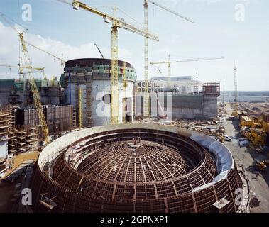 Blick nach Südosten auf das Reaktorgebäude auf der Baustelle des Kernkraftwerks Sizewell 'B', im Vordergrund drei Abschnitte Stahlliner für die Reaktorkuppel. Sizewell 'B' ist eines von zwei Kernkraftwerken an der Küste von Suffolk in der Nähe des Dorfes Sizewell. Sizewell 'A', sein Vorgänger, ist dabei, stillgelegt zu werden. Sizewell 'B' ist ein Druckwasserreaktor (PWR), der erste seiner Art in Großbritannien. John Laing plc wurde am 19. Mai 1987 der Auftrag für die wichtigsten Tiefbauarbeiten erteilt. Sizewell 'B' wurde 1995 fertiggestellt, af Stockfoto