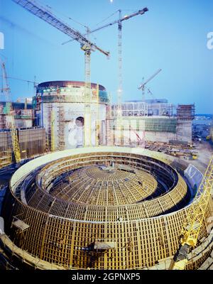 Blick nach Südosten in Richtung des Reaktorgebäudes auf der Baustelle des Kernkraftwerks Sizewell 'B', im Vordergrund drei Abschnitte Stahlliner für die Reaktorkuppel. Sizewell 'B' ist eines von zwei Kernkraftwerken an der Küste von Suffolk in der Nähe des Dorfes Sizewell. Sizewell 'A', sein Vorgänger, ist dabei, stillgelegt zu werden. Sizewell 'B' ist ein Druckwasserreaktor (PWR), der erste seiner Art in Großbritannien. John Laing plc wurde am 19. Mai 1987 der Auftrag für die wichtigsten Tiefbauarbeiten erteilt. Sizewell 'B' wurde in 1 abgeschlossen Stockfoto