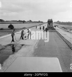 Ein Blick auf den Bau der Autobahn Birmingham nach Preston (M6), der ein Team von Arbeitern zeigt, die im Norden des Büros von Sektion B trockenen, mageren Beton legten. Die Arbeiten auf der Autobahn Birmingham-Preston (M6) zwischen den Kreuzungen J13 und J16 begannen im Juni 1960 und wurden von John Laing Construction Ltd. Durchgeführt.Abschnitt B war 6 1/2 Meilen lang zwischen Whitgreave und Beech. Stockfoto
