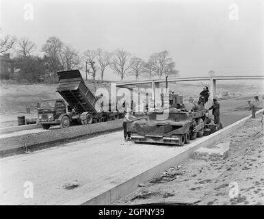 Ein Blick auf den Bau der Autobahn Birmingham nach Preston (M6), der ein Team von Arbeitern zeigt, die auf Abschnitt B der Autobahn eine konkretgebundene granulare Grundstrecke verlegten. Die Arbeiten auf der Autobahn Birmingham-Preston (M6) zwischen den Kreuzungen J13 und J16 begannen im Juni 1960 und wurden von John Laing Construction Ltd. Durchgeführt.Abschnitt B war 6 1/2 Meilen lang zwischen Whitgreave und Beech. Stockfoto