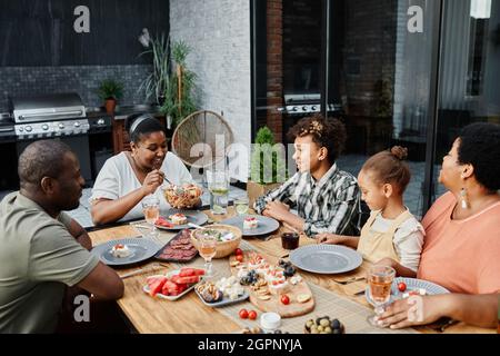 Porträt einer großen afroamerikanischen Familie, die am Tisch sitzt und gemeinsam im Freien zu Abend gegessen hat, Platz zum Kopieren Stockfoto