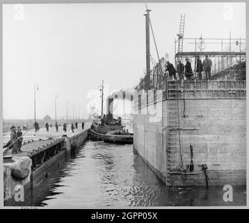 Ein Blick auf den Kühlwasserkaisson für die Coryton Ölraffinerie, die Tilbury Dock verlässt, um ihre Reise die Themse hinunter zu beginnen. Während des Zweiten Weltkriegs hatte John Laing &amp; Son Ltd einige der schwimmenden Caissons für den Hafen von Mulberry gebaut, die für die Landungen der D-Day verwendet wurden. Dieser 4,200 Tonnen schwere Betonwassereinlasskaisson wurde entlang des Hafens von Mulberry gebaut und 8 Meilen die Themse hinunter vom Tilbury Dock geschleppt, um am 14. März 1952 als Teil der Coryton Ölraffinerie installiert zu werden. Es wurde zwischen 1951 und 1952 erbaut. Fotos der Konstruktion finden Sie in den Alben JLP01/01/ Stockfoto