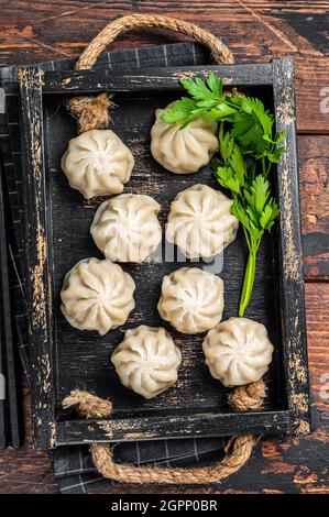 Momo Knödel in einem Holztablett mit Kräutern. Dunkler Holzhintergrund. Draufsicht Stockfoto