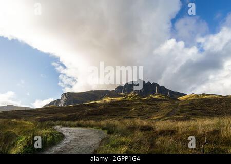 Pfad zum Old man of Storr in der goldenen Stunde mit dunkler Felsformation im Hintergrund, Isle of Skye, Schottland Stockfoto