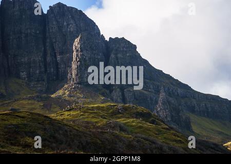 Der alte Mann von Storr in goldenem Licht, während der Sonnenuntergang in ungewöhnlicher Frontperspektive mit dunkler Felsformation im Hintergrund, Isle of Skye, Schottland Stockfoto