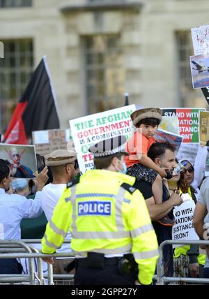 London, England, Großbritannien. Metropolitan Police bot im Dienst bei einer Demonstration in Whitehall, 2021. Kleiner Junge mit pakol-Hut, getragen von seinem Vater Stockfoto