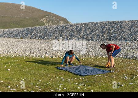 Junge kaukasische Touristen, die ein Zelt auf einem Campingplatz inmitten von Felsen in der Natur aufschlagen Stockfoto