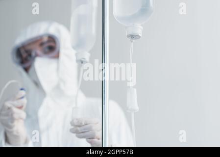 Arzt mit persönlicher Schutzausrüstung und Schutzbrille, die den Katheter auf dem Fallzähler hält Stockfoto