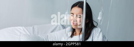 Kranke Frau mit geschlossenen Augen, die während der Therapie im Krankenhaus Schmerzen spürte, Spruchband Stockfoto