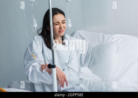 Brünette Frau mit geschlossenen Augen Schmerzen während der Therapie im Krankenhaus Stockfoto