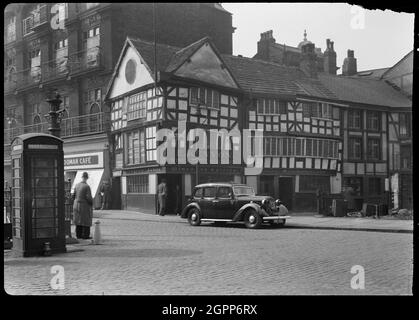 Old Wellington Inn, Old Shambles, Manchester, 1942. Außenansicht des Old Wellington Inn, mit der Vorderfassade in Old Shambles. Das ehemalige Haus, heute öffentliches Haus, stammt aus der Mitte des 16. Jahrhunderts und wurde in den 1970er Jahren um 30 Fuß verändert und erhöht. Mitte bis Ende der 1990er Jahre wurde es neben der Sinclairs Oyster Bar um 70 m nach Norden verlegt und 1999 wieder eröffnet. Das Gasthaus hat drei Stockwerke und einen drei-Bucht-Plan, mit den letzten Buchten, die gegabelt sind. In der linken Ecke befindet sich eine Splattür und in der Mitte der Südfassade eine Tür aus dem 20. Jahrhundert. Das Foto zeigt den Gasthof in seiner ursprünglichen Form Stockfoto