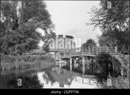 Flatford Bridge, Flatford Mill, East Bergholt, Babergh, Suffolk, 1930-1946. Flatford Bridge und Bridge Cottage vom Südufer des Flusses Stour aus gesehen. Bridge Cottage ist jetzt ein Besucherinformationszentrum und ein Geschäft des National Trust. Die Hütte zeigt in zwei Gemälden von John Constable, 'Boys Fishing' (1813) und 'View on the Stour near Dedham' (1822). Stockfoto