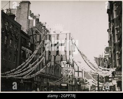 Fleet Street, City of London, Greater London Authority, 1953. Blick auf die Fahnen, die an den Gebäuden und im Zentrum der Fleet Street hängen, von der aus Dekorationen aufgereiht werden, für die Krönung von Elisabeth II. Die Krönung von Elisabeth II. Fand am 2. Juni 1953 statt. Die Flaggen, die in der Mitte der Fleet Street auf diesem Foto hängen, sind die Flaggen der City of London, die im linken oberen Viertel des St. George's Cross ein rotes Schwert zeigt. Stockfoto