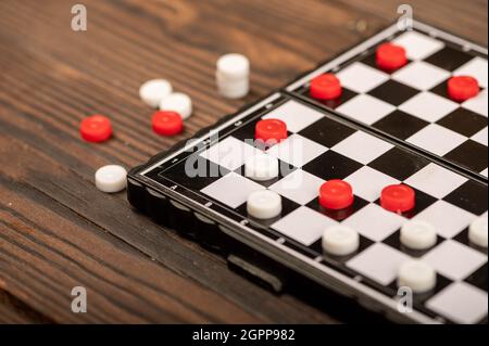 Ein Brett zum Spielen von Dame mit Chips auf einem Holztisch, Nahaufnahme, selektiver Fokus Stockfoto
