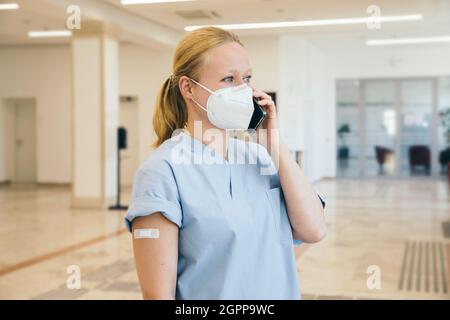 Österreich, Wien, Krankenschwester in Gesichtsmaske mit Smartphone Stockfoto