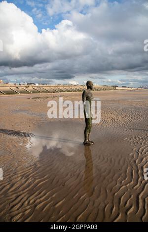 Ein Seitenblick bei Ebbe auf eine von Antony Gormleys „Another Place“-Skulpturen am Crosby Beach, Merseyside bei Ebbe im Spätsommer Stockfoto