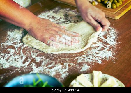 Zubereitung der italienischen Pizza. Hefeteig-Pizza in den Händen kneten Stockfoto