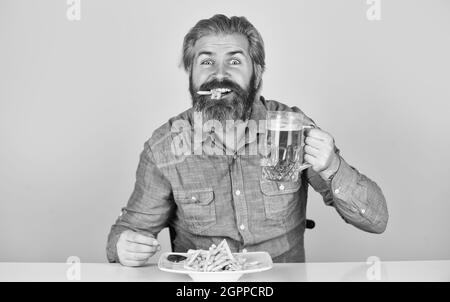 Pommes Frites Kartoffel. Kerl in der amerikanischen Bar Bier Glas trinken und essen Kartoffel. Cheers. Fußball im Fernsehen. american Fast Food. Glücklich bärtigen Mann Stockfoto