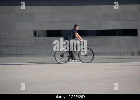 Junger Mann, der auf dem Fahrrad auf einer Straße reitet. Stockfoto
