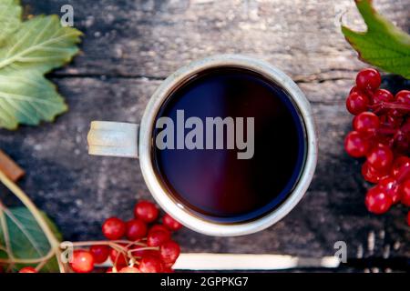 Natürlicher, gesunder Bio-Tee mit frischen Viburnum-Beeren bei natürlichem Sonnenlicht. Herbstliche Ästhetik. Hochwertige Fotos Stockfoto