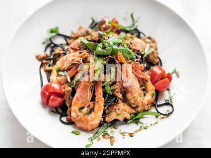 Spaghetti mit schwarzer Tintenfisch-Tinte, Garnelen und gemischtem Gemüse im Restaurant sizilien Stockfoto