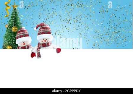 Zwei nette Schneemänner mit leerem Banner auf blauem Hintergrund mit Goldfolie Konfetti. Stockfoto