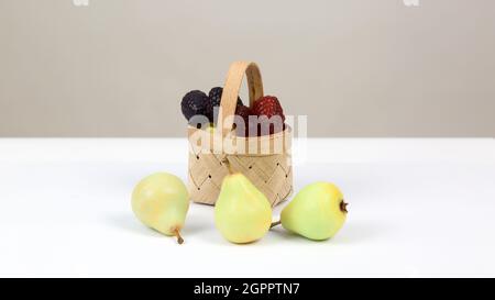 Handgemachte Seife in Form von Beeren und Birnen in einem Weidenkorb auf weißem Grund. Stockfoto