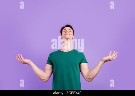 Foto von fröhlichen positiven jungen Mann heben die Hände leeren Raum Traum genießen isoliert auf lila Hintergrund Stockfoto