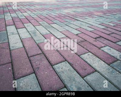 Struktur der Pflasterplatten: Ein Fußweg, der mit Ziegeln aus Pflasterplatten ausgekleidet ist. Hintergrund von Steinpflasterplatten. Stockfoto