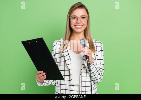 Foto Porträt junge lächelnde Geschäftsfrau tun Präsentation Zwischenablage Mikrofon isoliert pastellgrün Hintergrund Stockfoto