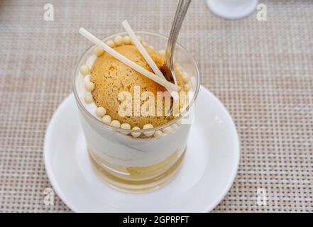 Baba au Rhum, oder Rum baba, serviert im Glas auf einem weißen Teller. Restaurant La Riviera in St. Regis Nursultan, Kasachstan Stockfoto