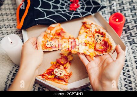 Helloween Pizza mit kleinen Papierkarren-O-Laternen-Kürbissen. Feiertagsfeier mit Kerzen und Kostümen. Menschen, die Essen essen Stockfoto