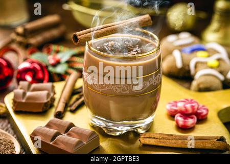 Heiße Schokolade mit Dampf oder Rauch, Weihnachtsgetränk, mit Lebkuchenmann im Hintergrund, Weihnachtsdessert Stockfoto