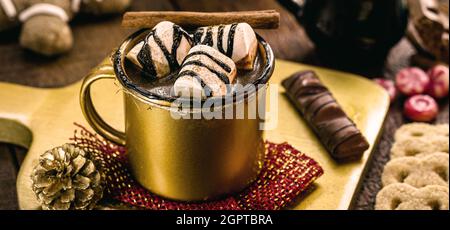 Heiße Schokolade in einer goldenen Tasse mit Salmmidinnen und Zimt Stockfoto
