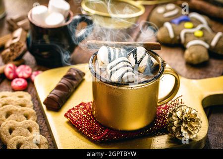 Heiße Schokolade mit Marschmalchen, Dampf oder Rauch, hausgemachtes Weihnachtsgetränk, mit Lebkuchenmann im Hintergrund Stockfoto